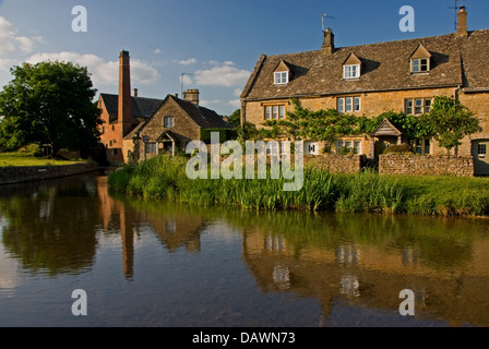 Cotswold village of Lower Slaughter with cottages and the old mill reflected in the River Eye . Stock Photo