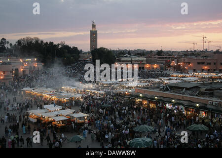 Smoke rises from the cookshops on Djamaa el-Fna square while the sun sets in Moroccon royal city Marrakech, Morocco, 8 April 2007. The famous Kutubiya mosque can be seen in the background. Its snake charmers, story tellers and cookshops attract masses of tourists and locals every day. Photo: Marijan Murat Stock Photo