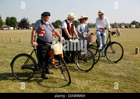 Men and women in period outfits on vintage bicycles. One man is dressed as an Onion seller. Stock Photo