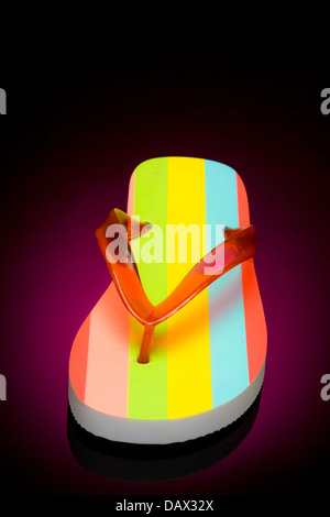 Single colour striped flip flop with red v shaped strap on a black background. Stock Photo