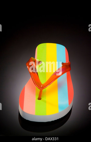 Single colour striped flip flop with red v shaped strap on a black background. Stock Photo