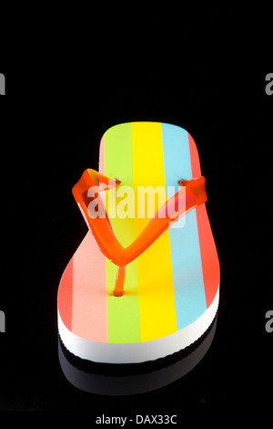 Single colour striped flip flop with red v shaped strap on a black background. Stock Photo