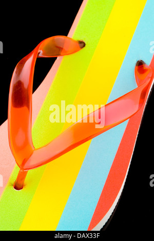 Closeup of the V shaped strap on a multicoloured flip flop sandal on a black background Stock Photo