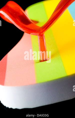 Closeup of the toe post section on a coloured striped flip flop on black background Stock Photo