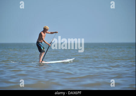 BARRY ISLAND, UK. 19th July 2013. The British heatwave continues and people flock to the beaches in South Wales. A man paddles through the water while standing on a surfboard. Photo credit Credit:  Polly Thomas / Alamy Live News Stock Photo
