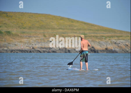 BARRY ISLAND, UK. 19th July 2013. The British heatwave continues and people flock to the beaches in South Wales. A man paddles through the water while standing on a surfboard. Photo credit Credit:  Polly Thomas / Alamy Live News Stock Photo