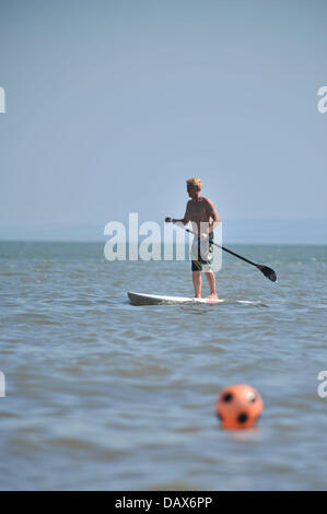 BARRY ISLAND, UK. 19th July 2013. The British heatwave continues and people flock to the beaches in South Wales. A man paddles through the water while standing on a surfboard. Photo credit Credit:  Polly Thomas / Alamy Live News Stock Photo