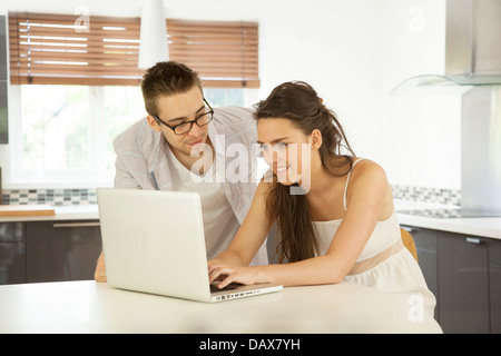 Young couple in a kitchen using a laptop together. Stock Photo
