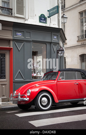 Red Volkswagen Beetle parked in front of consignment shop in the Marais, Paris France Stock Photo