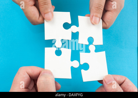 Two hands holding jigsaw puzzle pieces and putting them together Stock Photo