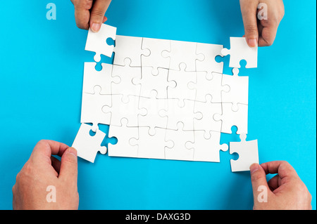 Two person holding jigsaw puzzle pieces and putting them together Stock Photo