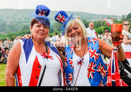Two women watch the 12th July Orange Order parade wearing Union Flag clothing Stock Photo