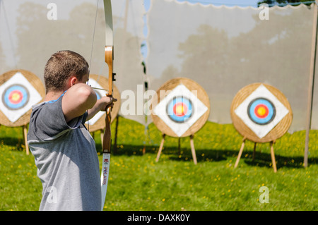 A man aims an arrow at an archery target Stock Photo