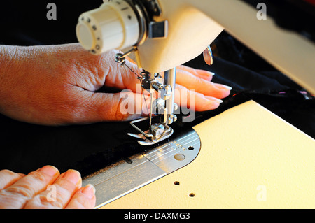 Woman using a domestic electric sewing machine to stitch black velvet, England, UK, Western Europe. Stock Photo