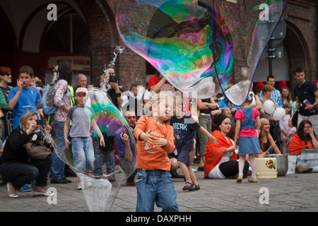 A girl catching big soap bubble during 'Industriada' 2013 street performance at Nikiszowiec main square. Katowice, Poland.A girl Stock Photo