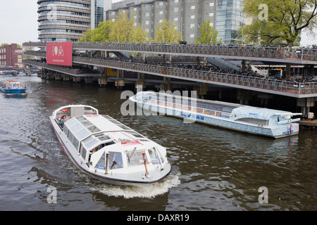 Boats on tours and large multi-level bike parking in Amsterdam, Netherlands, next to the Central Station. Stock Photo