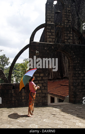 WOMAN & MULTI-COLOURED UMBRELLA ALUVIHARA ROCK CAVE TEMPLE MATALE SRI LANKA 11 March 2013 Stock Photo