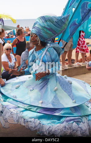 Bournemouth, UK 20 July 2013. A day of sensory delights, a feast of colour, music and dance. An African Caribbean style carnival procession takes place going along the beach seafront delighting visitors, as part of the Bournemouth Masquerade Festival, produced by Umoja Arts Network with dazzling vibrant costumes, sculpture and puppets performing to the sounds of the Caribbean. The event involves Bournemouth schools, some brilliant artists, and the local African Caribbean community to celebrate the rich cultural diversity in Bournemouth. Credit:  Carolyn Jenkins/Alamy Live News Stock Photo