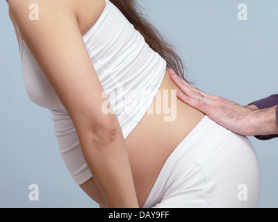 Pregnant woman with back pain getting a massage from her husband. Stock Photo