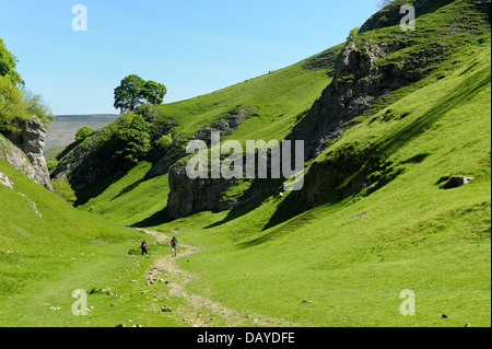 Two people in the distance walking through cave dale Castleton Derbyshire England uk Stock Photo