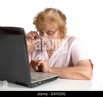The old woman in glasses looks at the screen notebook on a white background Stock Photo