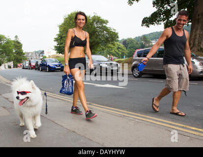 Bowness, UK. 21st July, 2013. A man and a woman dressed in summer clothes take a dog, complete with sunglasses, for a walk, in the hot summer weather in Bowness on Lake Windermere, UK. Credit:  Shoosmith Collection/Alamy Live News Stock Photo