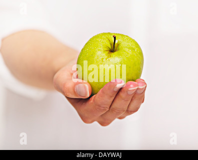 Woman's hand giving a green apple Stock Photo