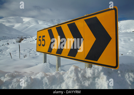 Corner warning sign on the 'Pigroot' (State Highway 85) in winter, Otago, South Island, New Zealand Stock Photo