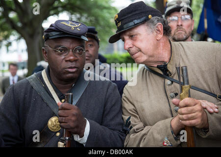 A Civil War re-enactor representing the all black 54th Massachusetts Volunteer Infantry stands with a Confederate re-enactor during a ceremony unveiling a memorial honoring the 54th on the 150th anniversary of the assault on Battery Wagner July 21, 2013 in Charleston, SC. The battle memorialized in the movie 'Glory' took place in Charleston and was the first major battle of an all black regiment. Stock Photo