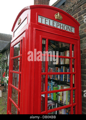 An old red British Telephone box turned into a British village eccentric lending library Stock Photo