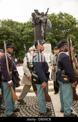 Civil War re-enactors representing the all black 54th Massachusetts Volunteer Infantry march past the Monument to the Confederacy during a ceremony unveiling a memorial honoring the 54th on the 150th anniversary of the assault on Battery Wagner July 21, 2013 in Charleston, SC. The battle memorialized in the movie 'Glory' took place in Charleston and was the first major battle of an all black regiment. Stock Photo
