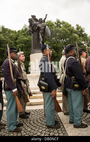 Civil War re-enactors representing the all black 54th Massachusetts Volunteer Infantry march past the Monument to the Confederacy during a ceremony unveiling a memorial honoring the 54th on the 150th anniversary of the assault on Battery Wagner July 21, 2013 in Charleston, SC. The battle memorialized in the movie 'Glory' took place in Charleston and was the first major battle of an all black regiment. Stock Photo