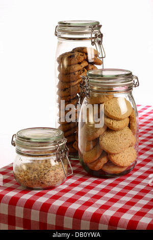 Chocolate and lavender cookies and crushed hazelnuts in a jar on rustic table with red gingham tablecloth and white background Stock Photo