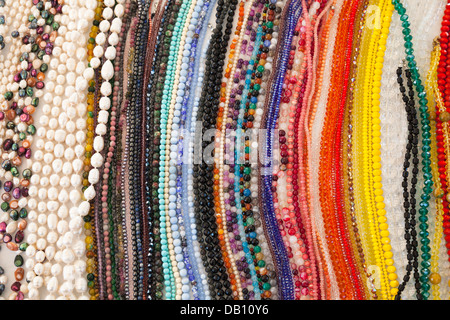 Colourful strings of beads and necklaces on a market stall in Italy, sourced from Punjab, India - multi-coloured Stock Photo