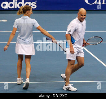 Former tennis pro German Steffi Graf (L) flirts with her husband and perfect match US Andre Agassi (R) during their mixed double charity match against Belgian pro Justine Henin and former pro Yugoslavian Goran Ivanisevic at SAP Arena stadium of Mannheim, Germany, 27 October 2007. The expected proceeds of 500,000 to 750,000 euro will be donated to the ?Children for Tomorrow? foundat Stock Photo