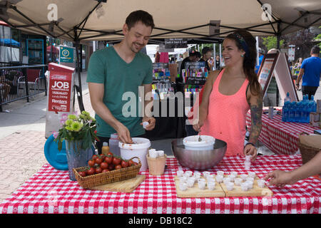 Cheerful man and woman spoon samples for the salsa tasting contest during the Sun and Salsa festival in the Kensington neighbourhood of Calgary, Alberta, Canada Stock Photo
