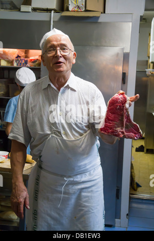 Italian cook showing a Tuscan Porterhouse steak (bistecca alla fiorentina) in his restaurant kitchen. In Florence, Italy Stock Photo