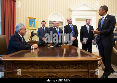US President Barack Obama jokes with members of the Chilean delegation as President Sebastián Piñera of Chile sits at the Resolute Desk following a bilateral meeting in the Oval Office June 4, 2013 in Washington, DC. Stock Photo