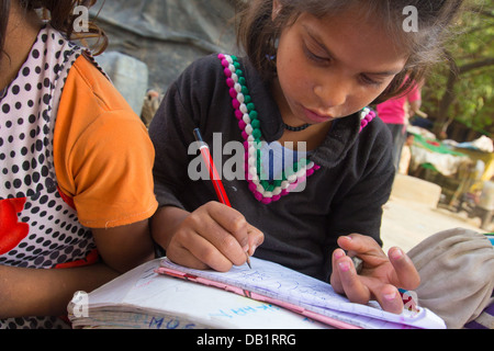 Young girl doing math in a notebook in a slum in New Delhi, India Stock Photo