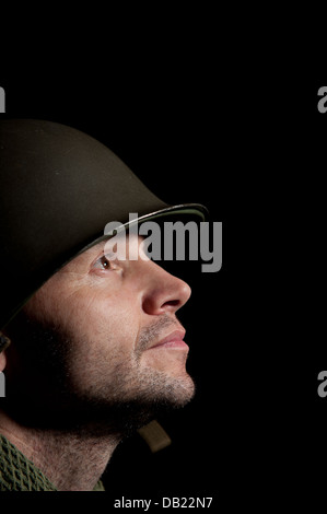 Spotlit profile portrait of an American WW2 soldier looking upward and against a black background. Stock Photo