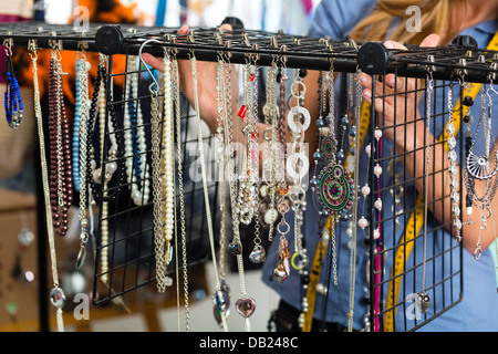 Freelance - jewelry designer working on a draft, different pieces of jewelry hanging in front Stock Photo