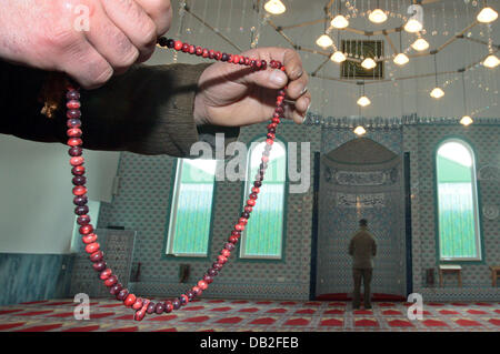 Muslims say their prayers in the prayer room of a mosque in Lindau, Germany, 17 December 2007. Pictured in the foreground are hands holding a chain of prayer beats called Misbaha (aka subha or Tespih). Photo: Karl-Josef Hildenbrand Stock Photo