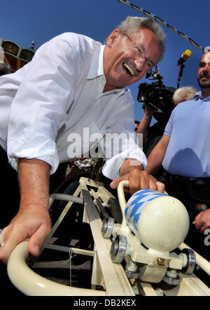 Mayor of Munich Christian Ude pushes Big Bertha at the historical part of Oktoberfest during a traditional press tour in Munich, Germany, 15 September 2011. The 39 kilogram heave canon, which was place at the folk festival in the 1960s, is pushed upwards and meassures the strength of the participants. Photo: FRANK LEONHARDT Stock Photo