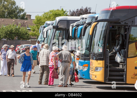 Tourists waiting to board coaches after visiting a tourist attraction, England, UK Stock Photo