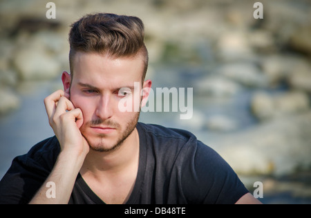Portrait of sad, worried or depressed young man outdoors thinking Stock Photo