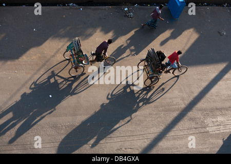 View from above of rickshaws casting shadows on the road as they ferry passengers along the streets of Chittagong Bangladesh