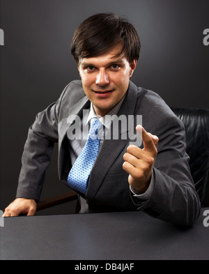 businessman sitting behind his desk looking at camera with hand raised Stock Photo