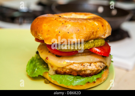 A turkey hamburger on an onion bagel with pepper jack cheese, pickles, grilled onions, Romaine lettuce, and tomato Stock Photo