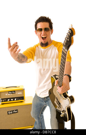 rowdy white young man rock musician holding black electric guitar pointing his finger yellow stack amplifiers white background Stock Photo