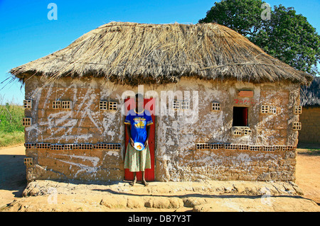 African Countries - Angola woman stands in front door small mud clay hut in Angila thatch roof rural living poverty hard Stock Photo